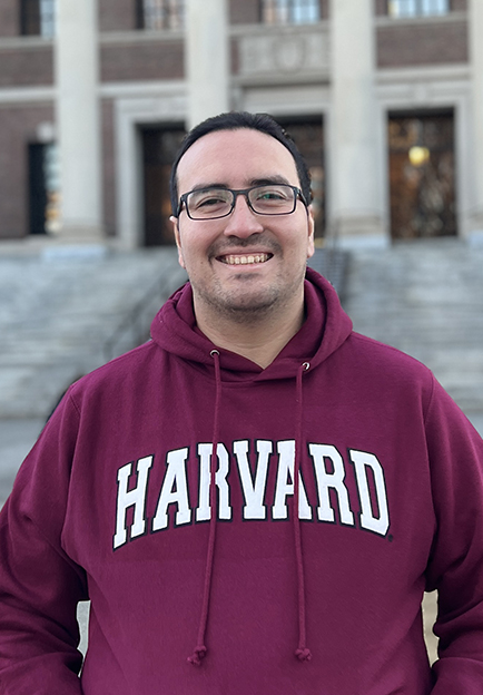 Foto de Sebastián Cisterna con un sweater que tiene el logo de Harvard University